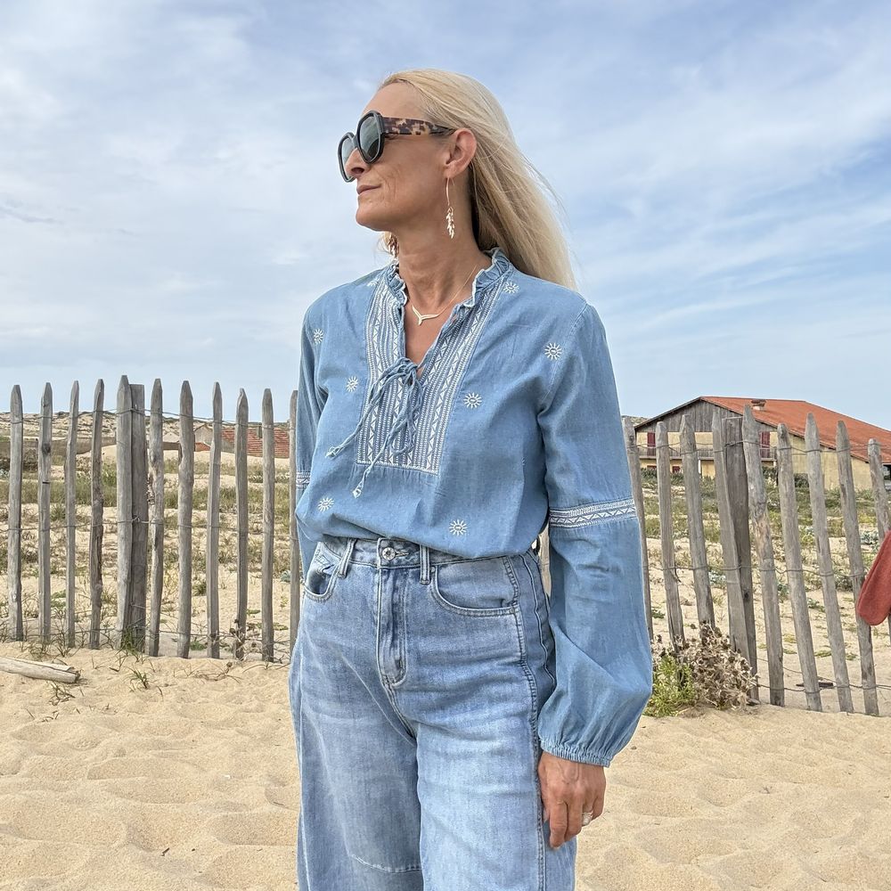 Blouse en jean brodée portée rentrée dans un pantalon